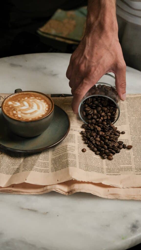 a person pouring coffee into a cup on top of a newspaper
